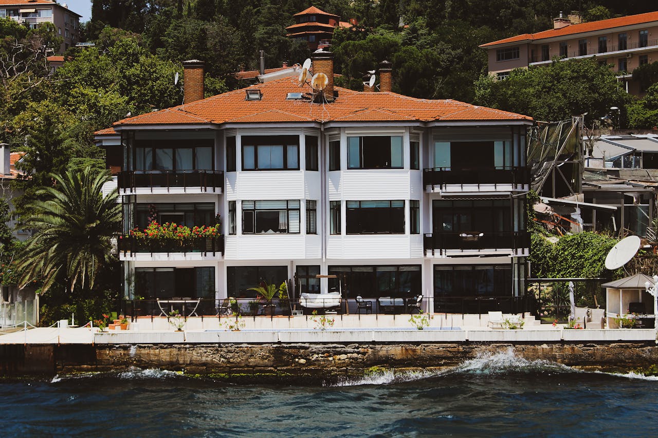 services-03 Elegant waterfront villa with red roofs in Kayseri, Turkey surrounded by lush greenery.
