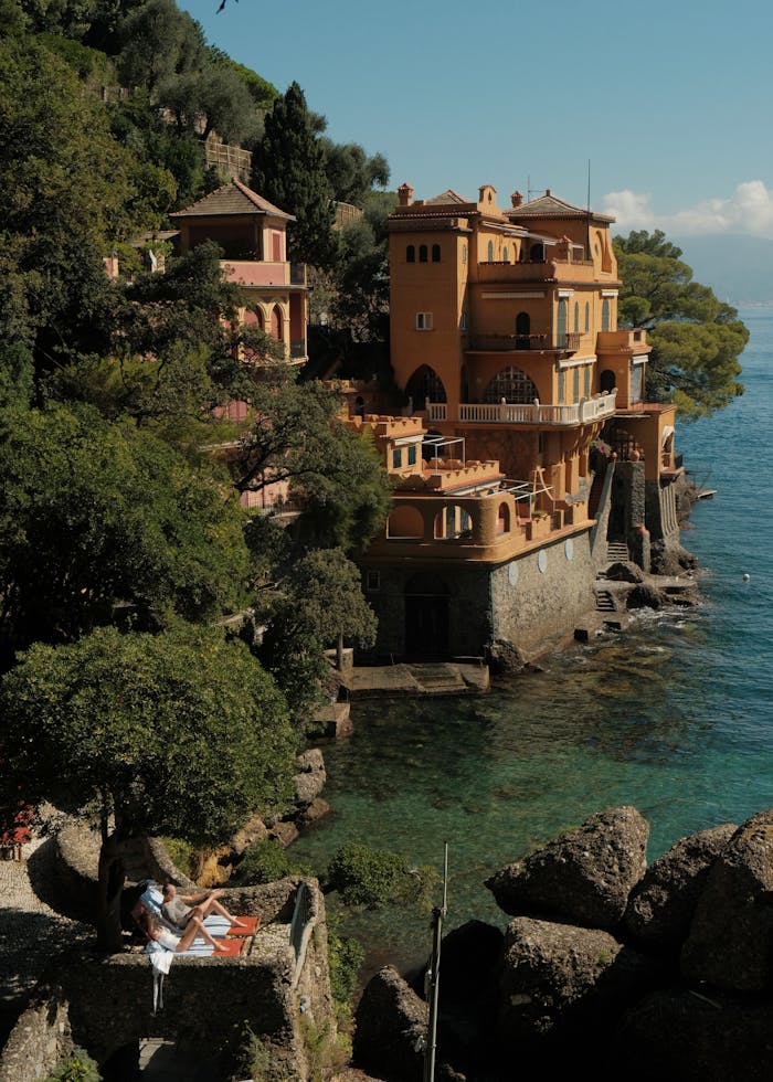 services-01 Beautiful villa on the rocky coast of Portofino, Italy, surrounded by lush greenery and turquoise sea.